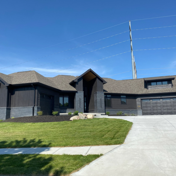 Modern custom-built home in Elkhorn, NE, featuring dark siding, a unique roofline, and a spacious driveway.