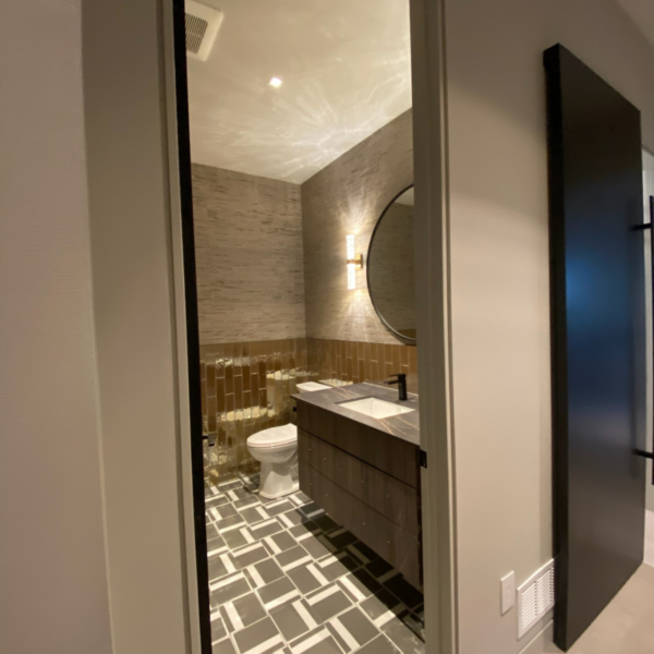Chic powder room with textured tile walls, warm accent lighting, and a custom wood vanity.