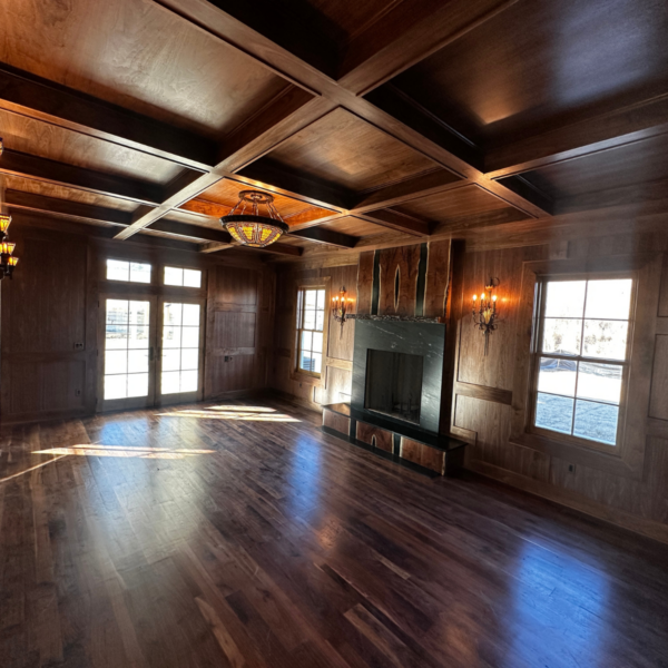 Grand living room with wood-paneled walls, coffered ceiling, and fireplace