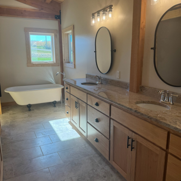 Rustic bathroom featuring a double vanity and classic clawfoot bathtub.