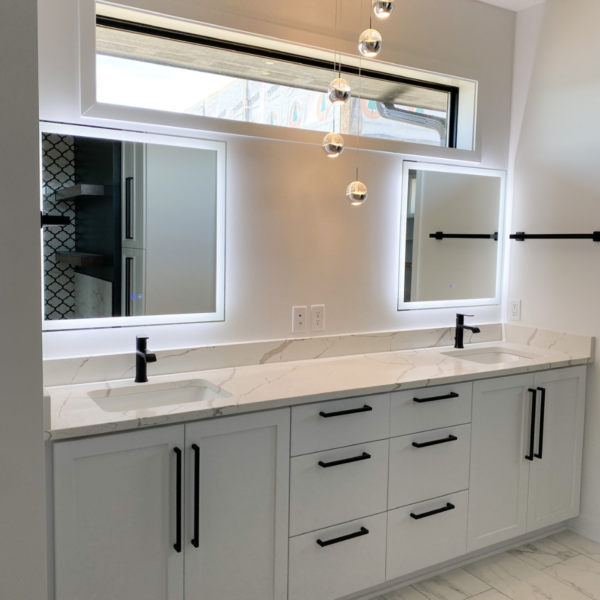 Master bathroom with a dual vanity, LED-lit mirrors, and modern pendant lighting.