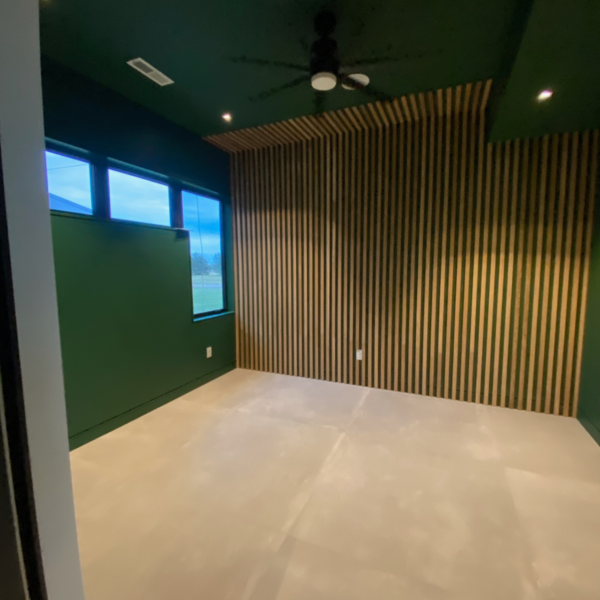 Modern home office with green walls and slatted wood accent wall.