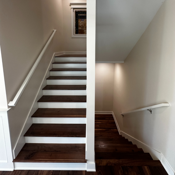 Modern wooden staircase with white risers and railings in a custom-built home.