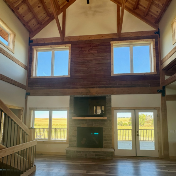 Grand living room with vaulted ceilings, exposed wooden beams, and a stone fireplace.