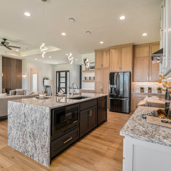 Spacious kitchen with a waterfall granite island, pendant lighting, and high-end appliances.