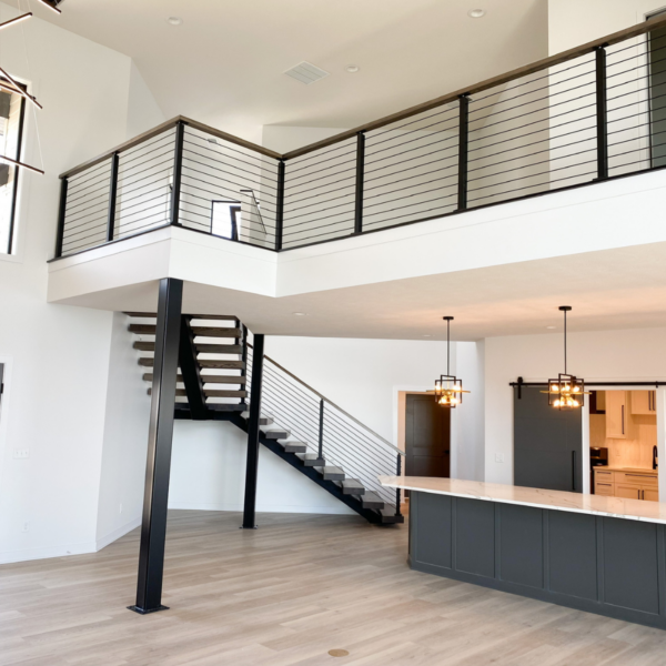 Open-concept great room with a floating staircase, black railings, and modern pendant lighting.