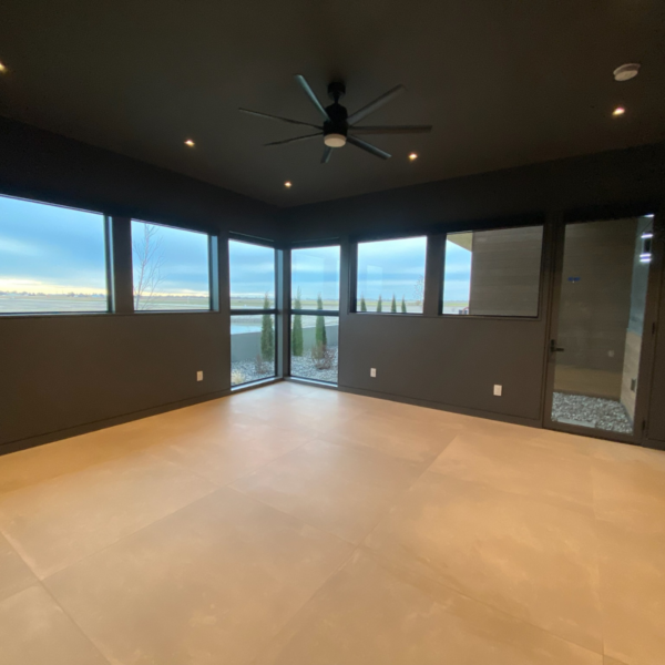 Spacious black-walled room with panoramic windows and a ceiling fan.