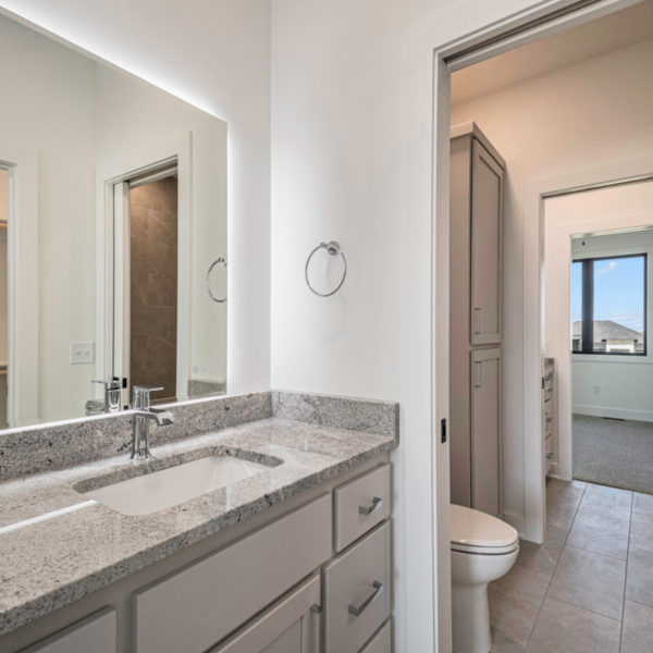 Contemporary bathroom with a sleek LED mirror, granite vanity, and neutral tones.