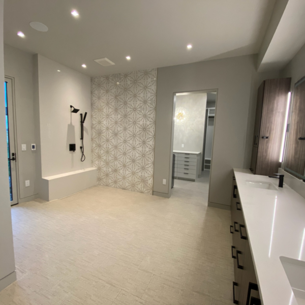 Spacious master bathroom with patterned tile accent wall and double vanity.