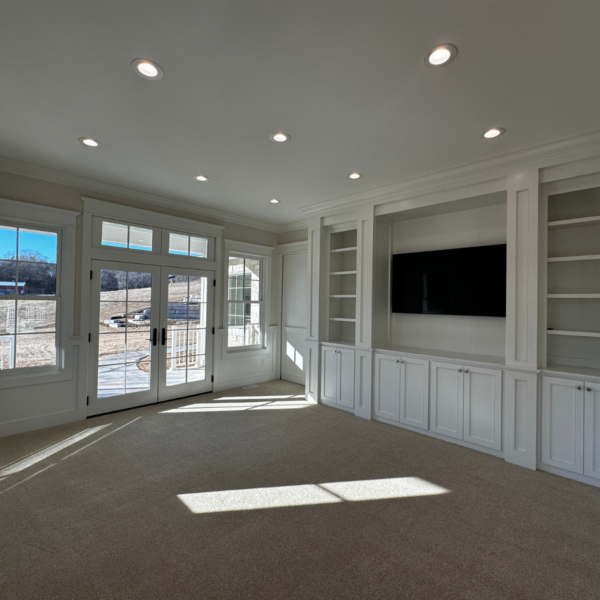 Living room with built-in shelving, a TV niche, and French doors leading to an outdoor space.