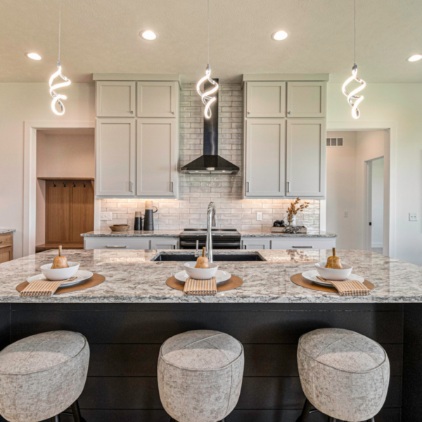 Open-concept kitchen with stylish pendant lighting, a granite island, and a tile backsplash.