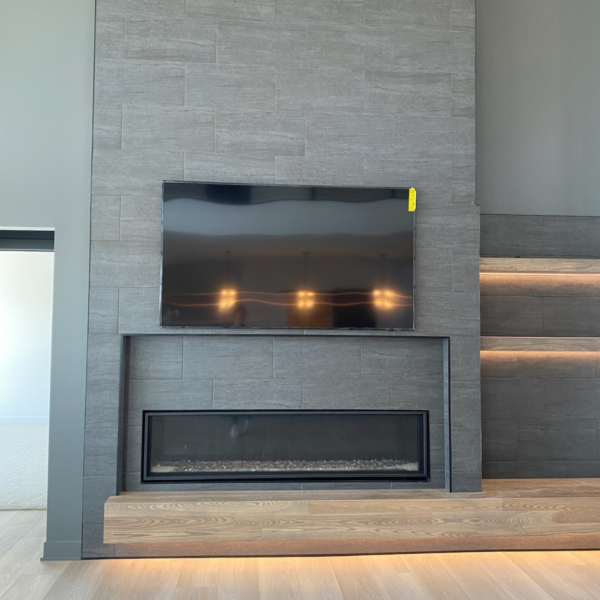 Modern fireplace feature wall with a built-in TV and recessed lighting in a custom-built home.
