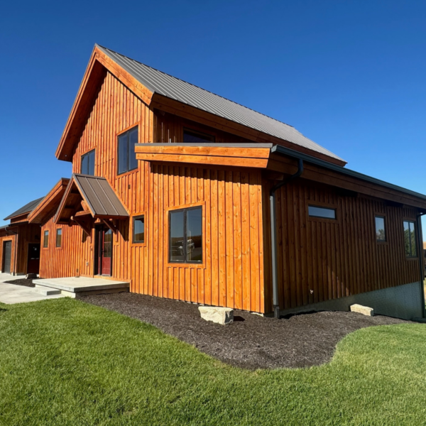 Side view of a modern timber home with rustic wood siding and a metal roof.