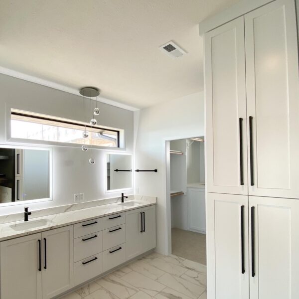 Modern master bathroom with a dual vanity, LED mirrors, and sleek white cabinetry.