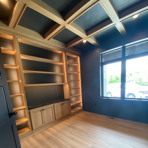 Home office with custom-built wood shelving and a large window for natural light in an Elkhorn, NE, custom home.