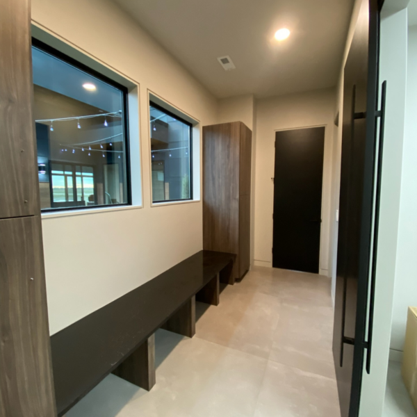 Sleek mudroom with custom-built cabinets, a black stone bench, and large windows.