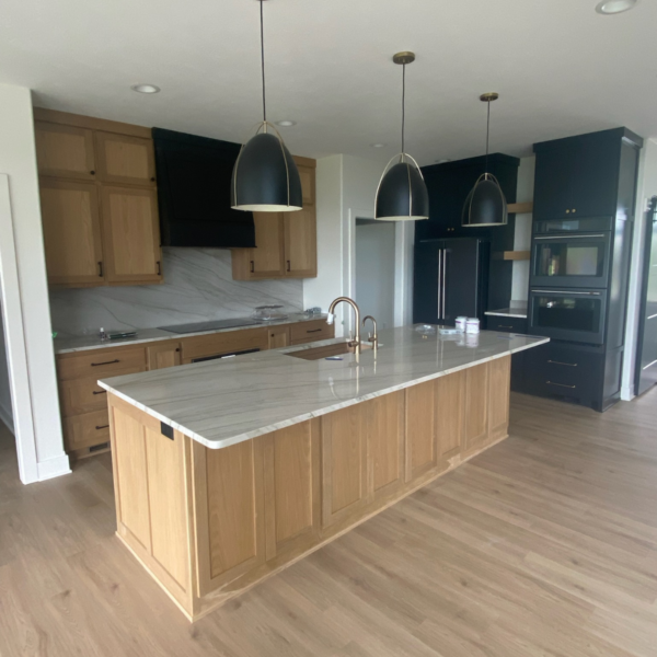 Luxury kitchen in a custom-built home featuring a marble island, wood cabinetry, and pendant lighting.