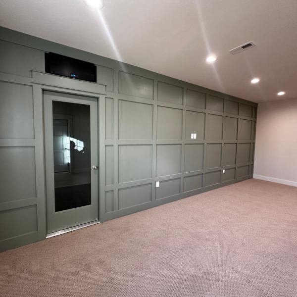 Green accent wall with built-in paneling and hidden door