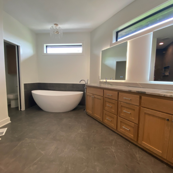 Master bathroom with a freestanding soaking tub, dual vanity, and modern lighting in a custom Elkhorn, NE, home.