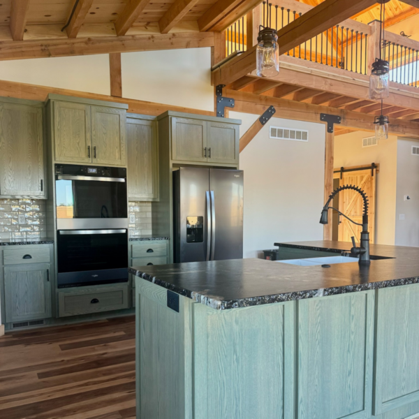 Custom-designed kitchen with rustic green cabinetry and black countertops.