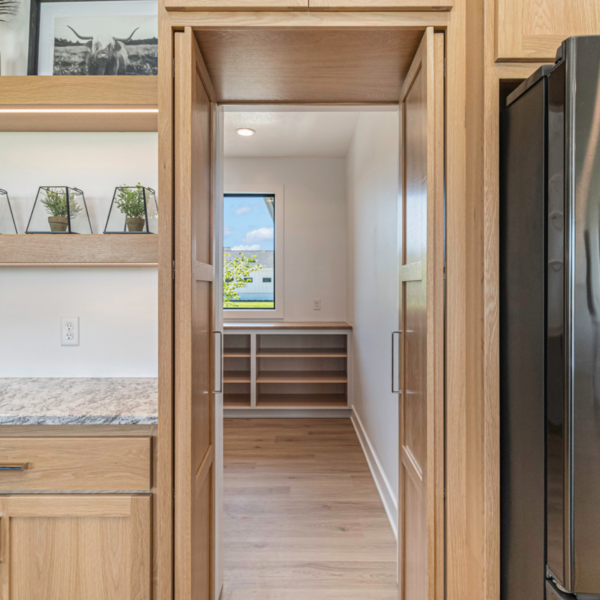 A hidden walk-in pantry with built-in shelving behind custom cabinet doors.
