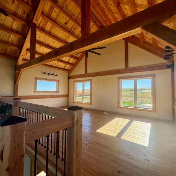 Sunlit loft space with exposed wooden beams and scenic views.