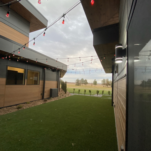 Enclosed outdoor courtyard with warm wood paneling, modern lighting, and string lights.