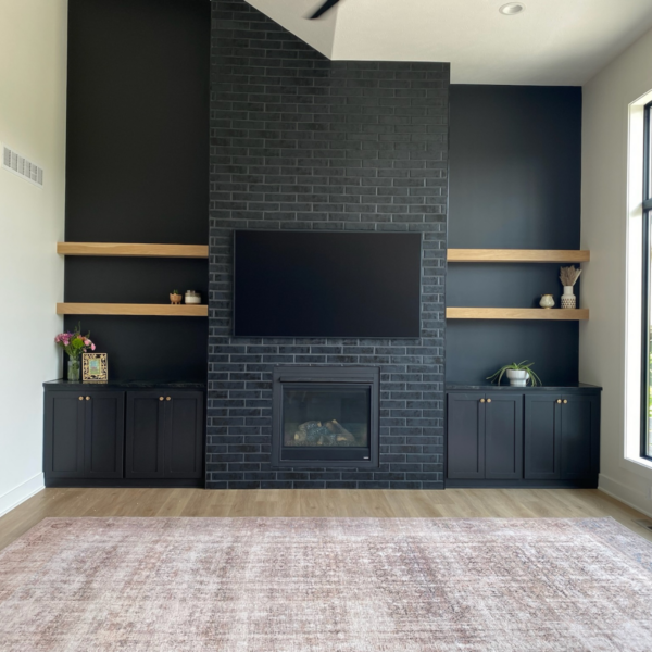 Custom-built living room with a black brick fireplace, wood shelving, and modern cabinetry.