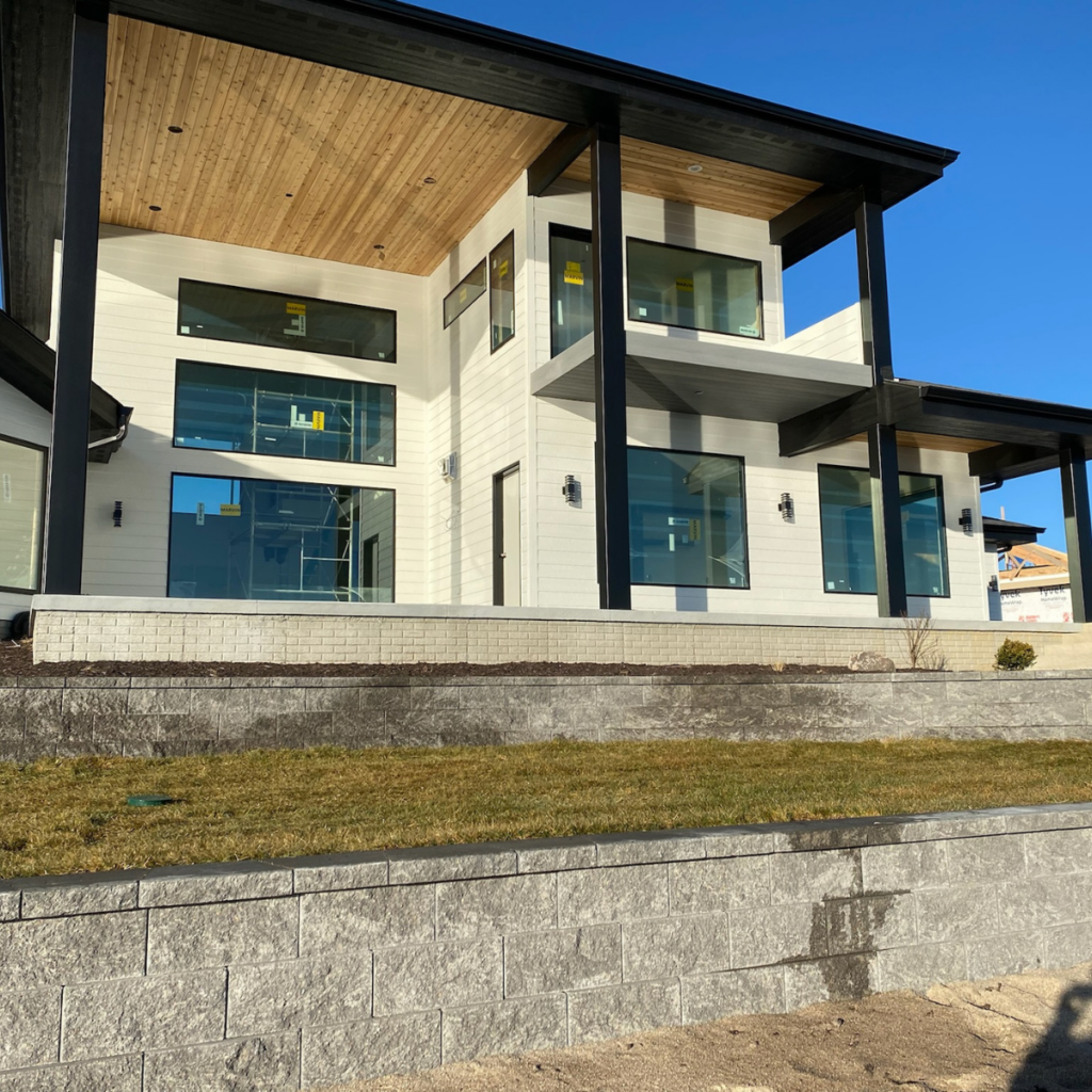 Contemporary two-story home exterior with large windows, wood-accented ceilings, and a covered patio.