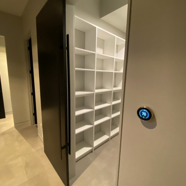 Walk-in pantry with custom-built white shelving and a modern sliding door.