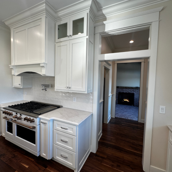 Close-up of a kitchen with a gas range, pot filler, and detailed cabinetry