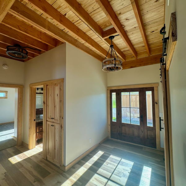 Entryway of a timber home featuring rustic wooden doors and ceiling beams.