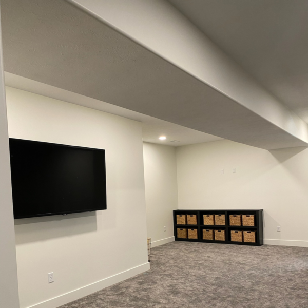 Finished basement with a mounted TV, built-in storage, and recessed lighting.