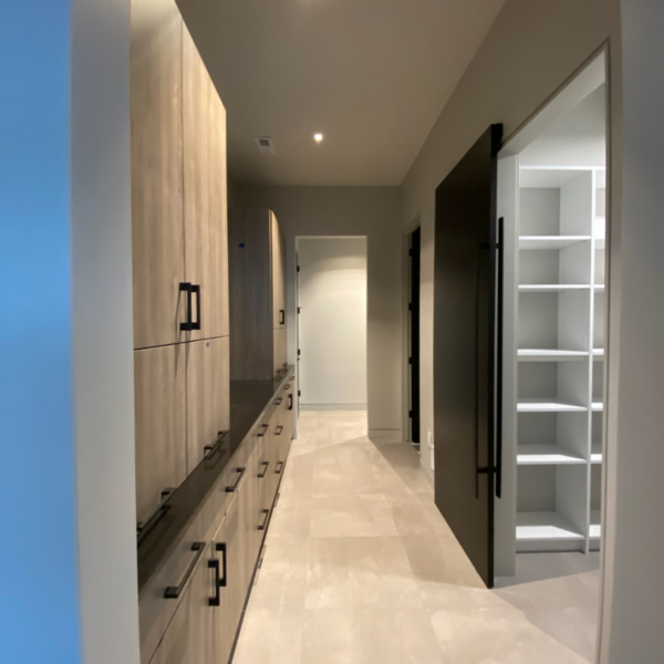 Modern hallway with built-in cabinetry, sleek black doors, and recessed lighting.
