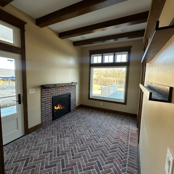 Cozy sitting area with brick flooring, wooden beams, and a fireplace