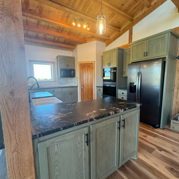 Modern farmhouse kitchen with black countertops and stainless steel appliances.