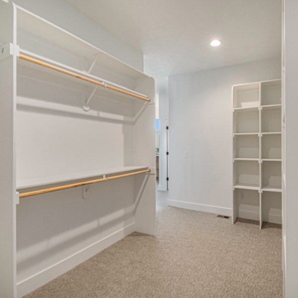 A large walk-in closet with built-in shelving, hanging space, and soft carpeting.